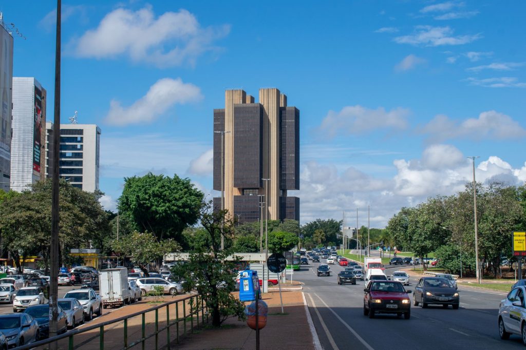 Copom sinaliza cautela após corte da Selic e aponta desaceleração da economia Vista externa do Banco Central do Brasil em Brasília sob um céu vibrante.