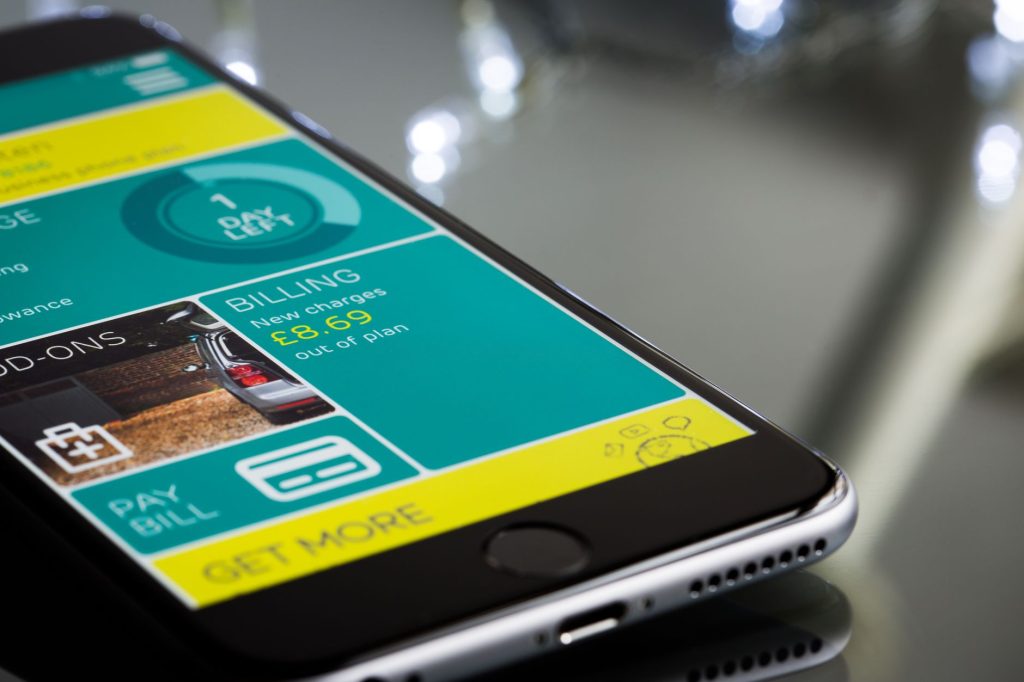 Pix Automático poderá ser usado em contas-salário a partir de julho de 2027 Smartphone exibindo a interface de um aplicativo de cobrança sobre uma superfície reflexiva.